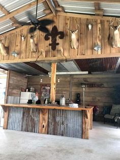 an outdoor bar with deer heads mounted on the wall above it and ceiling fans hanging from the rafters