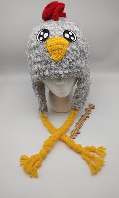 a knitted hat with a chicken on it's head and two yellow tassels around the brim