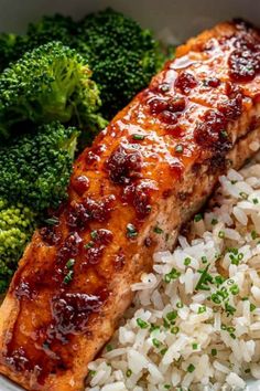 a bowl filled with rice, broccoli and salmon next to some kind of sauce