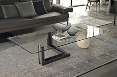 a glass coffee table sitting on top of a carpeted floor next to a couch