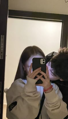 a man and woman taking a selfie in front of a mirror with their cell phones