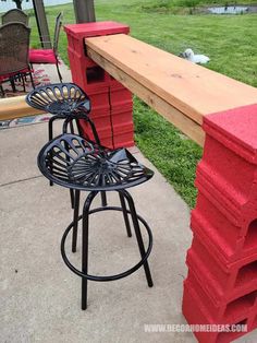 two chairs and a table sitting on the side of a sidewalk next to a grassy field