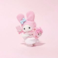 a pink stuffed animal with a bow on it's head holding a small doll