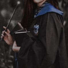 a woman with long red hair is holding a wand and wearing a harry potter costume