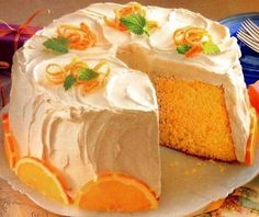 a cake with white frosting and oranges on it is sitting on a plate