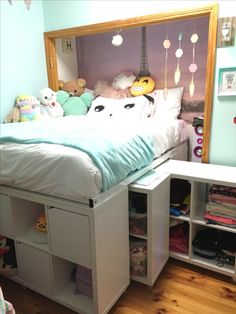 a bed with drawers underneath it and stuffed animals on the headboard in front of it