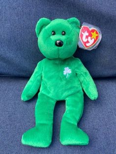 a green teddy bear sitting on top of a blue couch next to a heart shaped lollipop