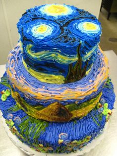 a three tiered cake decorated with blue, yellow and green icing art work