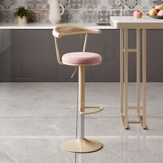 a pink stool sits in front of a counter with fruit on it and a vase