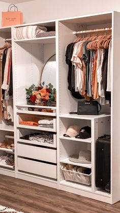 an organized closet with clothes and suitcases on the shelves, along with other items