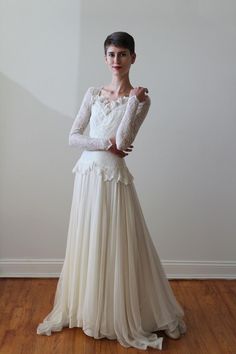 a woman in a white dress standing on a wooden floor with her arms around her waist