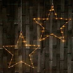 some lights are hanging on the side of a wooden fence as if they were made to look like stars