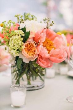 a vase filled with flowers on top of a table next to wine glasses and candles