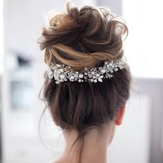 a woman wearing a bridal hair comb with pearls and crystals on it's head