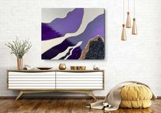 an abstract painting hangs on the wall above a white dresser and sideboard in a modern living room