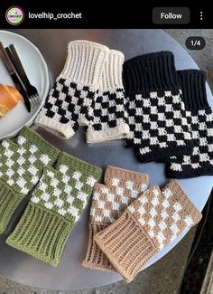 four knitted mittens sitting on top of a table next to a plate of food