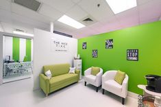 an office with green walls and white chairs