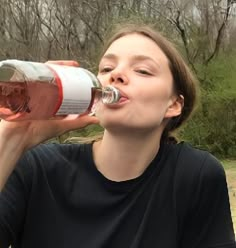 a woman drinking from a red and white bottle