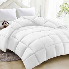 a white comforter on a bed in a room with pillows and stuffed animals next to it