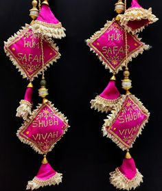 two pink and gold tassels with the word saah written on them, hanging from strings