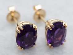 Fit for royalty, these earrings feature bright bursts of color from the amethysts and an excellent shine from every facet. The perfect size to transition from day to evening, these lovely earrings are sure to be a favorite of your jewelry wardrobe.Metal: 14K Yellow GoldGem: 2 Amethyst totaling 2.22 CaratsGem Measurements: 5.8 x 7.8 mm, OvalMarks: “14K” Stamped on the Findings Classic Purple Drop Earrings, Gold Amethyst Gemstone Earrings, Purple Oval Fine Jewelry Earrings, Purple Oval Earrings With Gemstone Accents, Yellow Gold Amethyst Earrings Hallmarked, Classic Purple Gemstone Earrings, Faceted Amethyst Round Earrings, Amythest Stud Earrings, Amethyst Studs