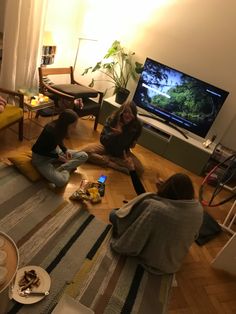 three people sitting on the floor watching tv