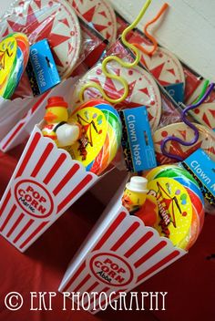 some candy and candies are sitting in small boxes on a red cloth covered table