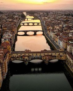 an aerial view of a bridge over a river with buildings and bridges in the background