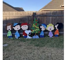 a group of cartoon characters standing in front of a fence with a christmas tree on it