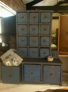 an old dresser with many drawers and pictures on it