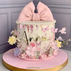 a pink and white cake with flowers on the top is adorned with a large bow