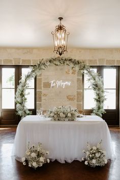 a table with white flowers and greenery is set up in front of a stone wall