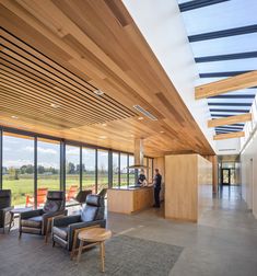 a large open room with lots of windows and wooden ceilinging, along with leather chairs