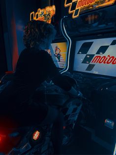 a person sitting on a motorcycle in front of a neon sign and video game machine