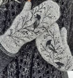 two mittens with birds on them are shown in front of a woman's face