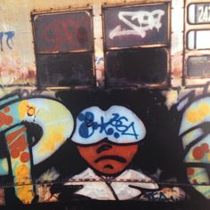 graffiti on the side of a train car with an image of a person wearing a hat