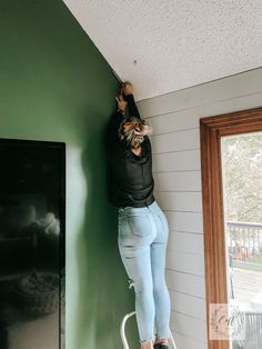 a woman climbing up the side of a green wall