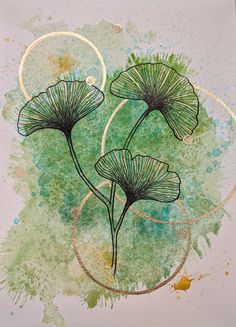 two green flowers on a white paper with gold circles and paint splattered around them