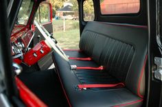 the interior of an old truck with red trim and black leather seat covers on it