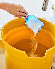 a person is pouring water into a yellow bucket