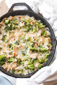 a skillet filled with chicken and broccoli covered in cheese