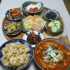 a table topped with bowls filled with different types of food next to rice and cucumbers