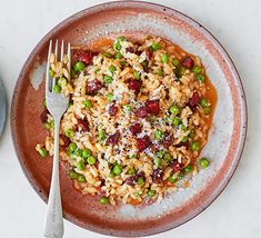 a bowl filled with rice and peas on top of a white table next to a fork