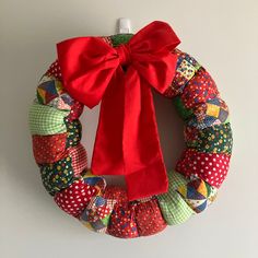 a colorful wreath with a red bow hanging on the wall next to a white wall