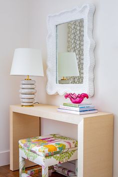 a white desk with a mirror, lamp and stool in front of it on top of a hard wood floor