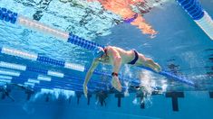 a woman swimming in a pool with her back turned to the camera and wearing a blue swim suit