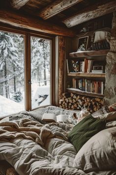 a bed with pillows and blankets on it in front of a window that looks out onto the snow