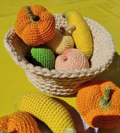 small crocheted fruits and vegetables in a basket on a yellow tableclothed surface