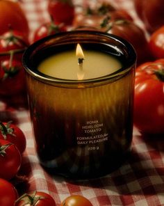 a candle sitting on top of a checkered table cloth next to tomatoes and tomatoes