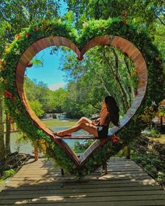 a woman is sitting on a heart shaped bench